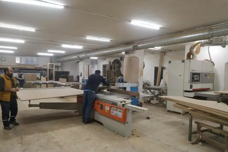Atölye ekibi ebatlama makinesinde panel kesiyor